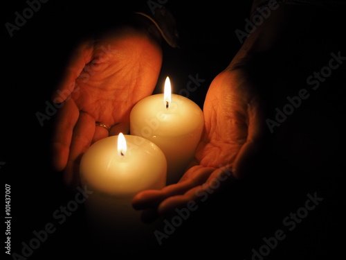 candle and hands on a black background