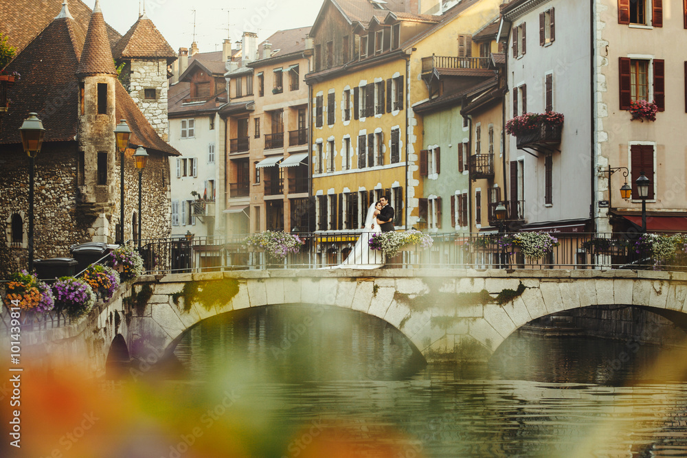Obraz premium Bride and groom hugging on old romantic bridge over river and ch