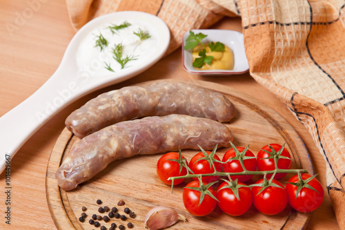 sausages in natural casing on a cutting board with cherry tomato