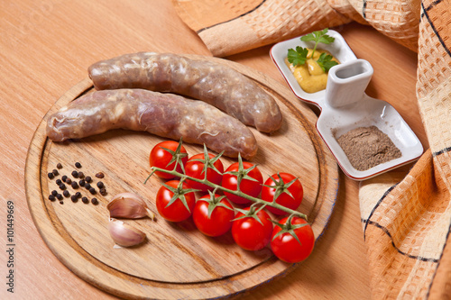 sausages in natural casing on a cutting board with cherry tomato