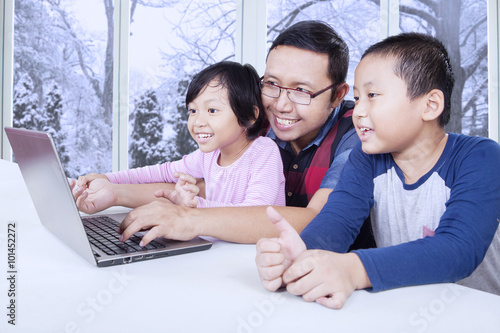 Dad with two kids using laptop at home © Creativa Images