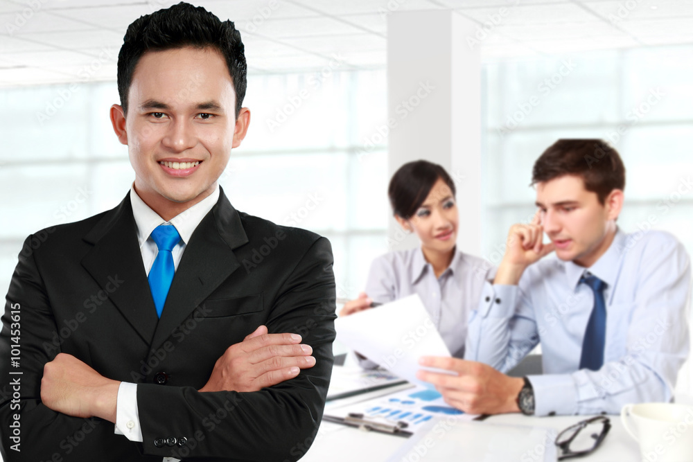 Young asian businessman, with his team behind. isolated in white Young asian businessman, with his team behind. isolated in white