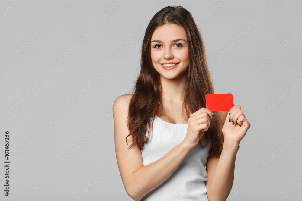 Smiling woman showing blank credit card in white t-shirt, isolated over gray background Smiling woman showing blank credit card in white t-shirt, isolated over gray background