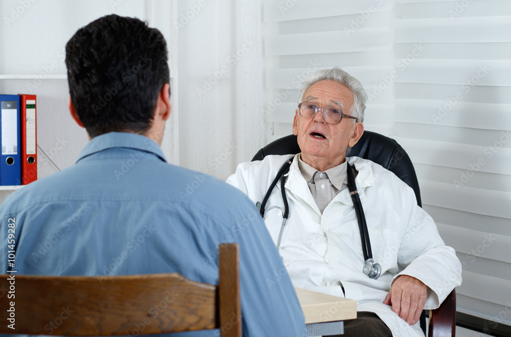 Male patient having consultation with old Doctor in consulting r Male patient having consultation with old Doctor in consulting r