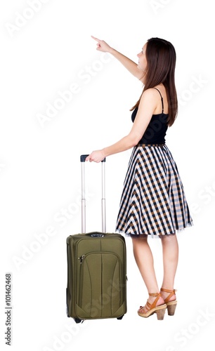 Back view of pointing woman with suitcase looking up.