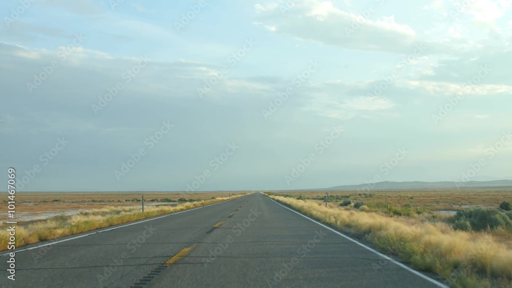 A car drives down a rural road at sunset. A car drives down a rural road at sunset.