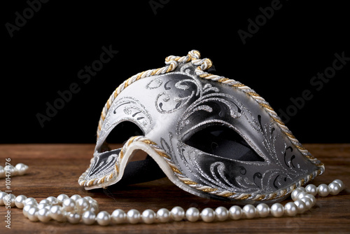 mask carnival white, black and gold on wood with pearl necklace on black background