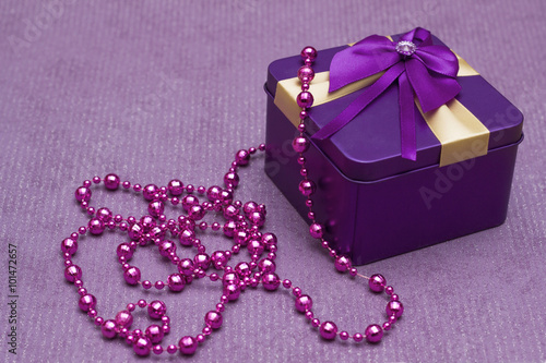 gold box with purple bow and pearls