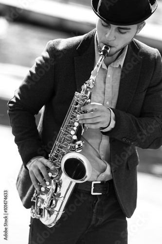Canvas Print Young man playing on saxophone on the riverside