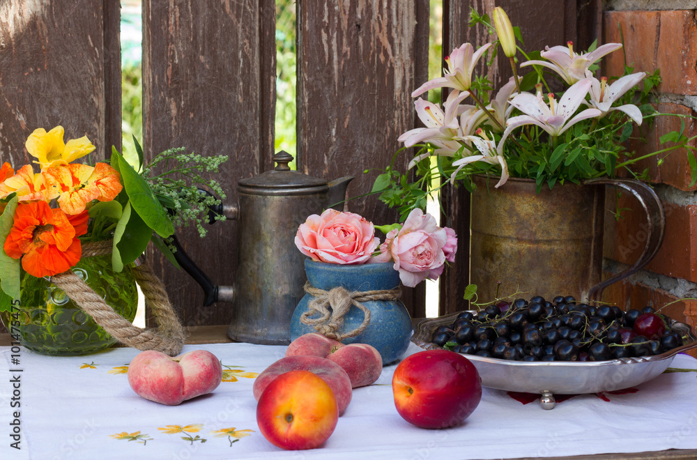 столик у забора с фруктами и цветами из садового участка