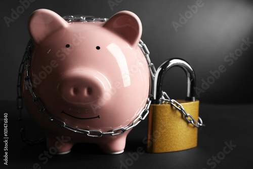 Piggy bank and chains on gray background