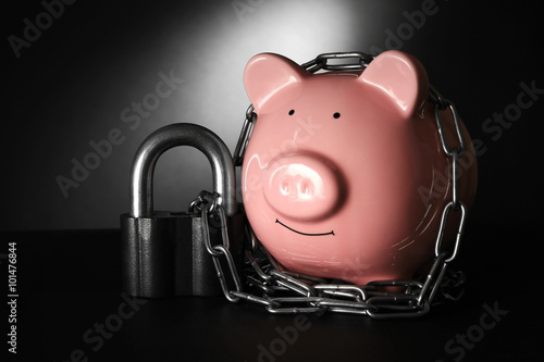 Piggy bank and chains on dark background