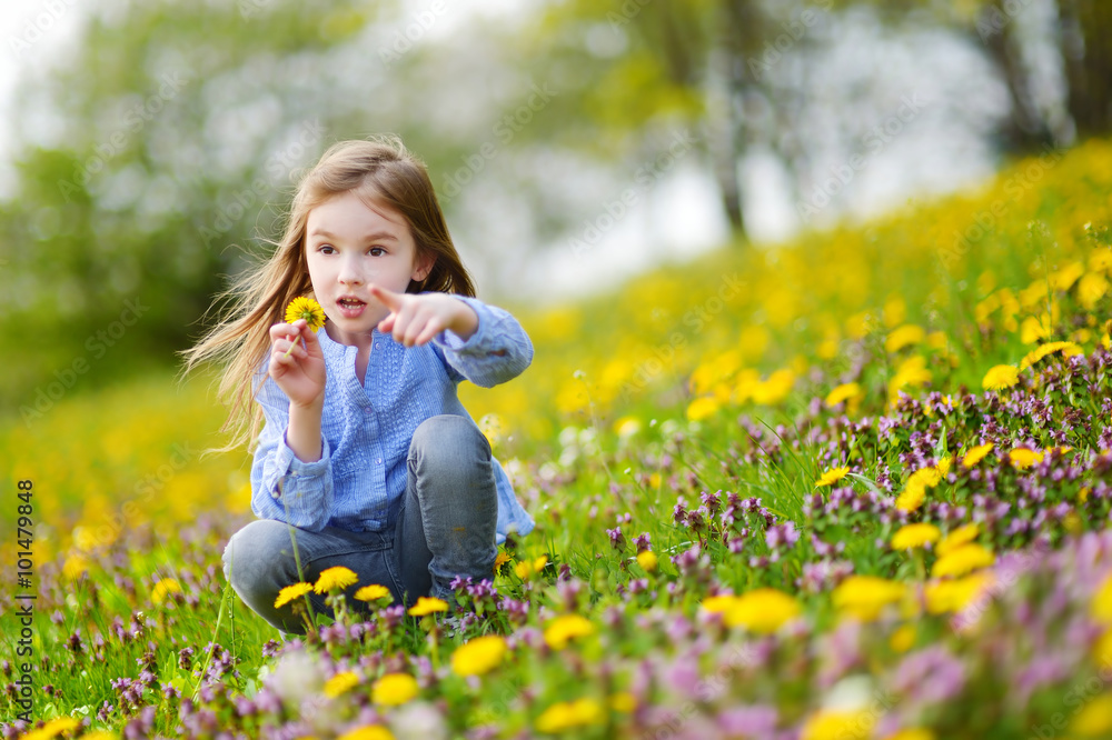 Adorable little girl in blooming dandelion flowers Adorable little girl in blooming dandelion flowers
