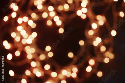 Golden Christmas lights on dark wooden background, blurred