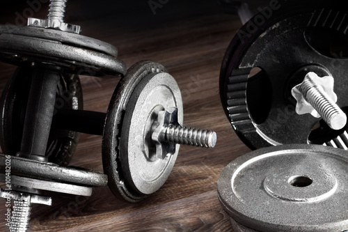 Composition of dumbbells and barbells on the wooden background