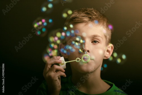 Young boy blowing iridescent bubbles