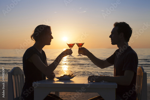 Couple having a romantic diner on a beach with cocktails