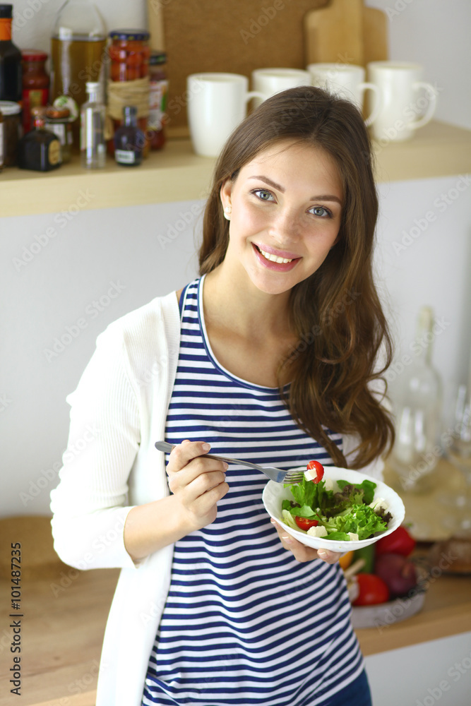 Young woman eating salad and holding a mixed salad Young woman eating salad and holding a mixed salad