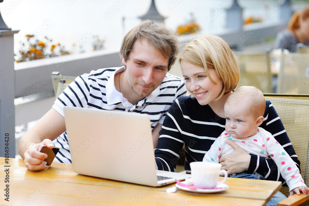 Young parents with their sweet baby in outdoors cafe Young parents with their sweet baby in outdoors cafe