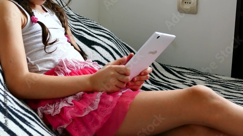 teen girl  playing tablet internet game sitting on bed  photo