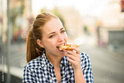 Teenager eating pizza in street