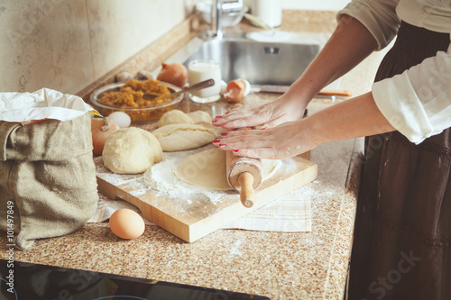 Female hand rolled sheet of dough with rolling pin