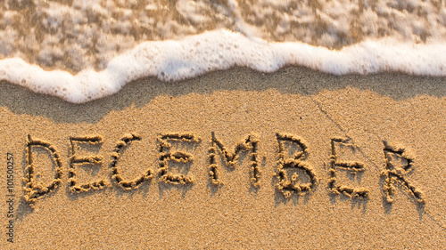 Inscription DECEMBER on a gentle beach sand with the soft wave (months of the year series)