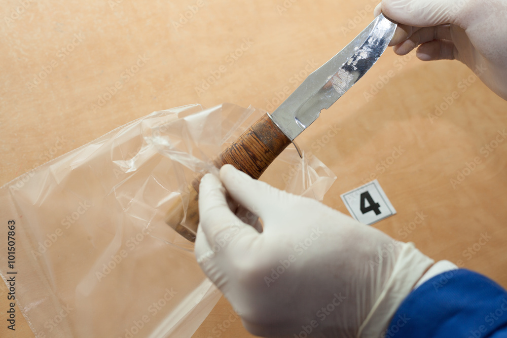 Ταπετσαρία expert through a magnifying glass looking at a bullet at the crime scene
