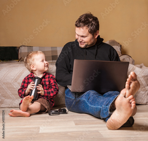 Young father working at home with computer and his child