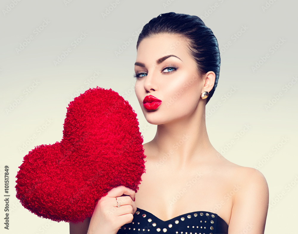 Gorgeous young brunette woman with heart shaped red pillow - obrazy, fototapety, plakaty 