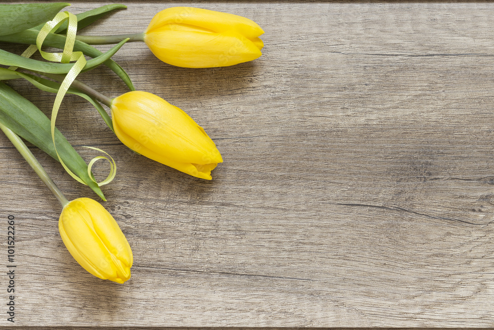Naklejka premium Żółte tulipany na drewnianych deskach