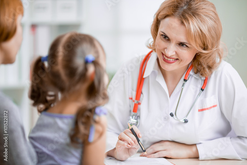 Family doctor consulting mother and kid photo