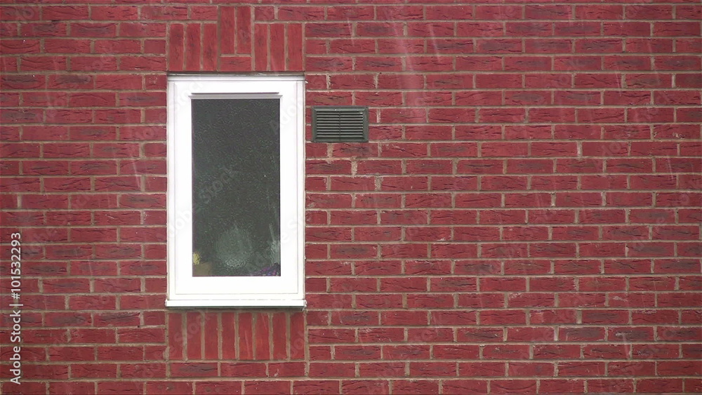 Snow falling on a red brick house background with a small white-framed PVCu type window. Snow falling on a red brick house background with a small white-framed PVCu type window.