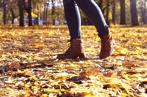 Female legs in boots on autumn leaves © Africa Studio