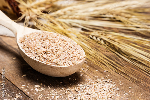 Closeup of wooden spoon filled with wheat bran photo