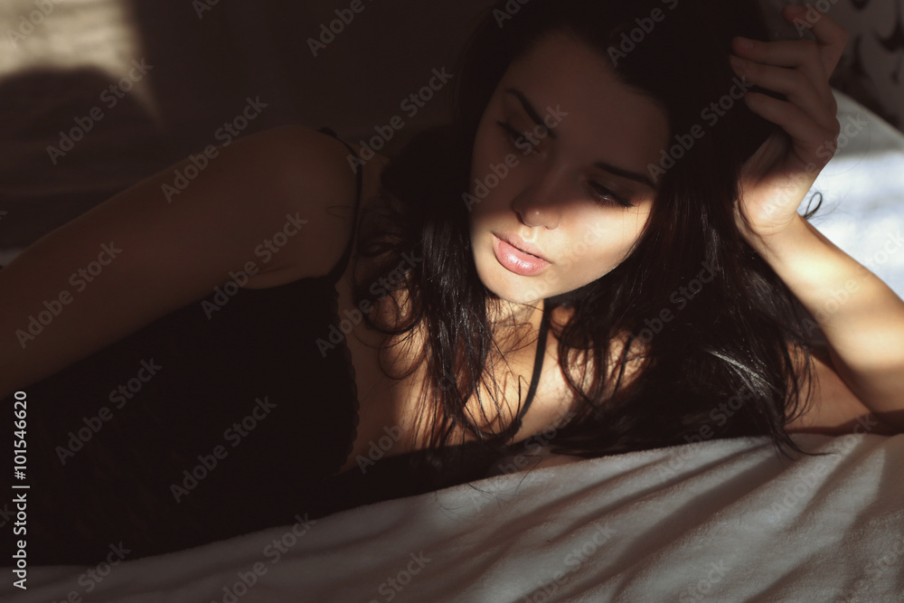 woman with dark hair in lace lingerie dress lying in bed in the morning woman with dark hair in lace lingerie dress lying in bed in the morning
