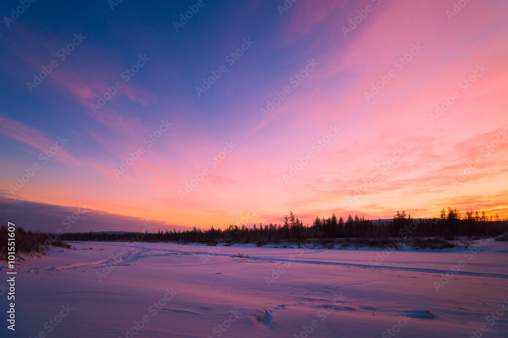 Winter landscape with forest, clouds and sunset 