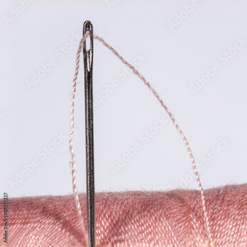 Macro view of threaded needle in a pink spool photo