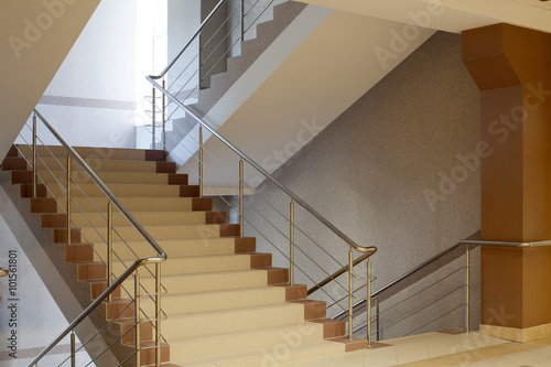 Brown staircase with metal railing, gray wall