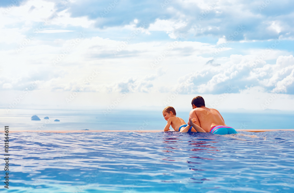 happy father and son enjoy beautiful seascape from infinity pool, vacation concept