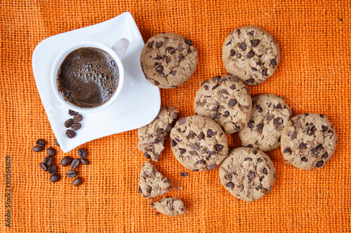 Chocolate chip cookies and cup of coffee shot on jute colored cl