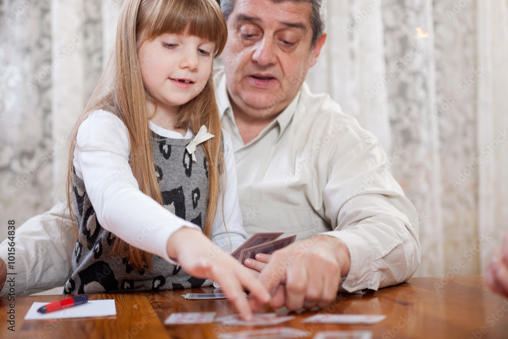 happy grandfather retired plays cards with his granddaughter