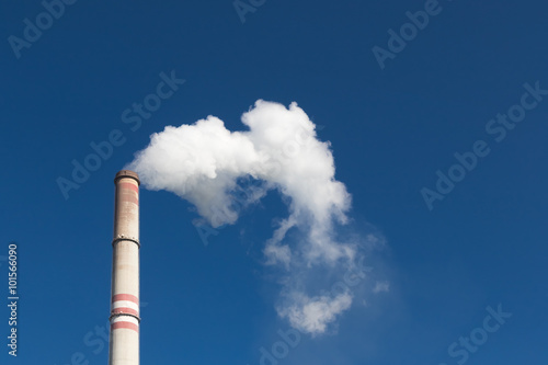 Industrial exhaust pipe with smoke against the sky