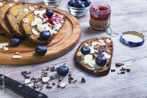 On a light wooden table sliced bread with fruits and nuts