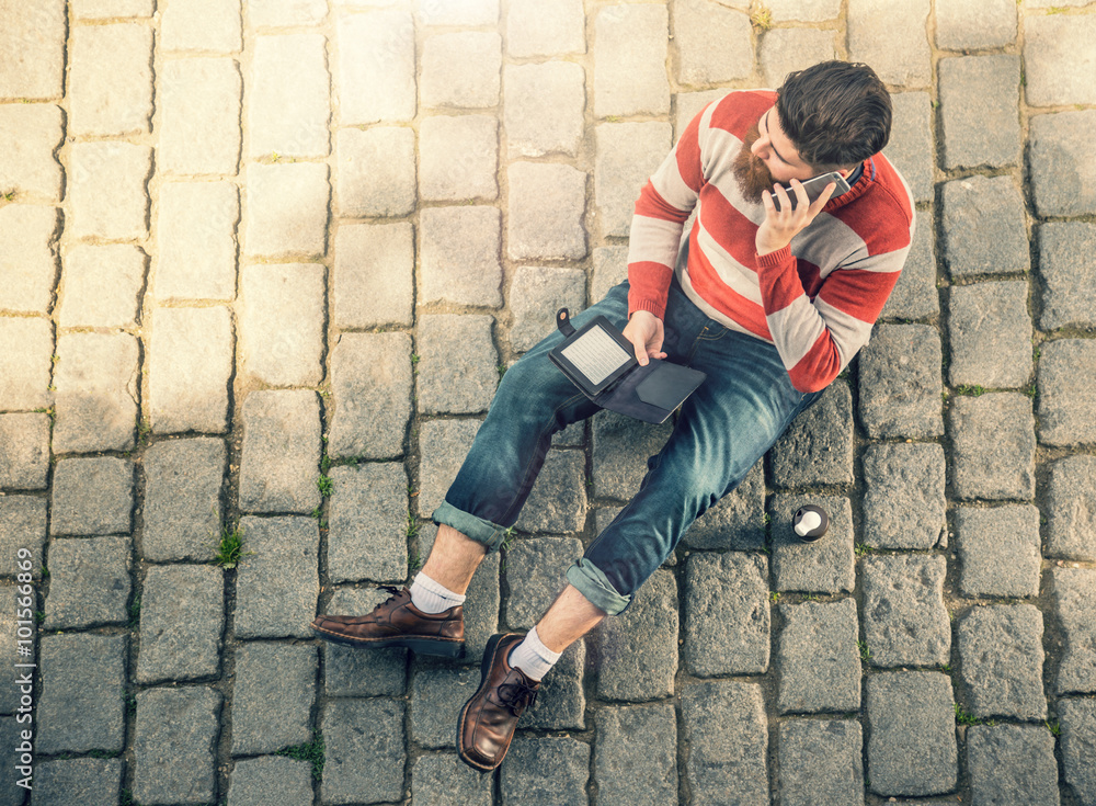 Young hipster man sitting and using cellphone Young hipster man sitting and using cellphone