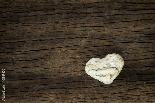 Stone in the shape of heart on natural wooden background