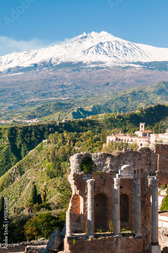 View of some columns in the stage of the greek theater in Taormina and a perspective of snowy mount Etna