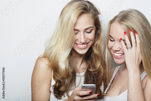 Two happy women friends sharing social media in a smart phone 