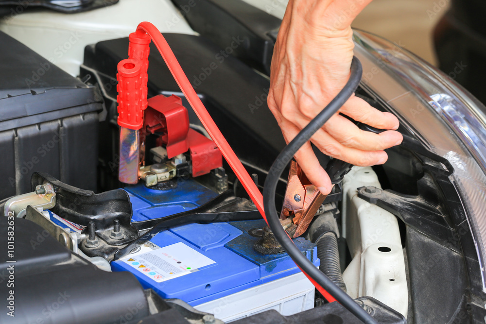 Car mechanic uses battery jumper cables charge a dead battery. Car mechanic uses battery jumper cables charge a dead battery.