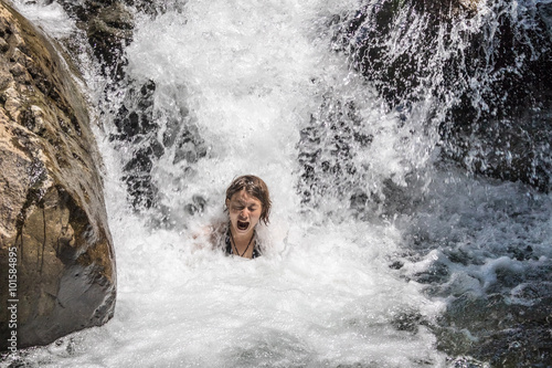Young girl swimming in the water at the waterfall